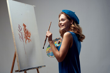 woman artist in blue beret palette easel drawing art creative hobby gray background