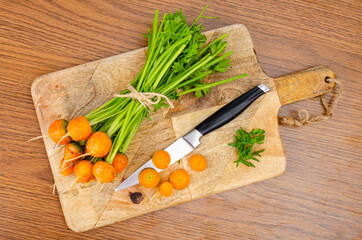 Round orange carrot on wooden board with knife.