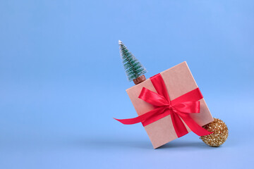 Banner with gift box with red bow and Christmas tree decorations on festive blue background with blurred bokeh and copyspace for your text. Christmas or New Year celebration concept
