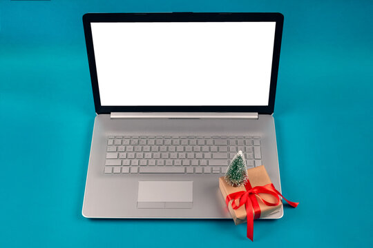 Mockup image of laptop computer and present box with red bow on green background with copyspace for your text. Shopping season, black friday and cyber monday concept. Online shopping