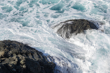 Sea waves with foam on rocks coast