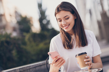 Photo portrait of girl holding phone paper cup smiling outdoors