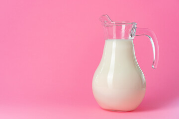 Glassware with fresh milk against pink pastel background
