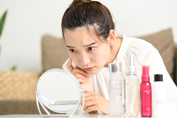 鏡を見ながら肌トラブルに悩む女性