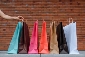 Close up a lot of colorful shopping bags on a brick wall background.