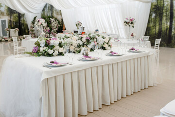 party reception table decorated with flowers: plates, forks, knives and wine glasses.