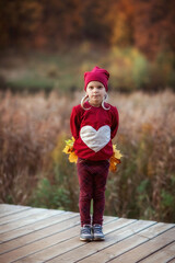 Fototapeta premium girl walks in the autumn by the lake in the Park, playing with leaves, autumn bouquet, happiness, childhood