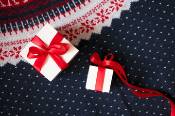Gift boxes with red bow from ribbon on winter sweater