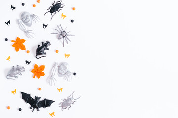 Halloween border on white with orange, black and silver holiday decor. Silver bats and ghosts flying around, copy space, gothic holiday flat lay