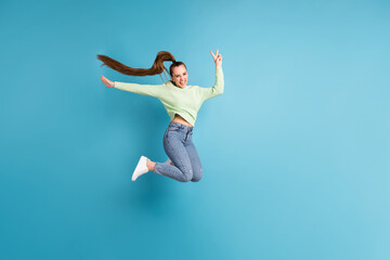 Fototapeta na wymiar Full length body size side profile photo of jumping girl with long hair showing v-sign isolated on vibrant blue color background