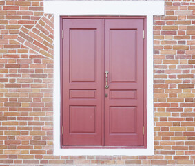 a wooden dark red door with a white frame in a brown brick wall. concept of new opportunities, a new way of development.