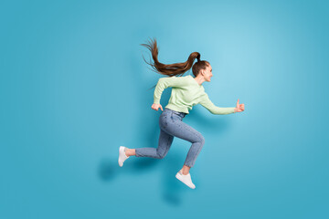 Full length body size side profile photo of jumping high running fast girl with long hair ponytail isolated on bright blue color background