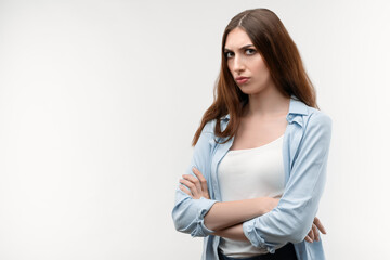 Portrait of beautiful brunette girl looking at camera suspiciously. Studio shot, white background. Copy space