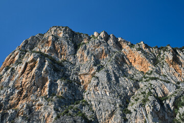 Gray rocks at high altitude. Alps top on blue sky. Rough rocky stones. Red stones on a blue background. The tops of the yellow peaks of the rocks.