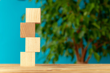 Wooden blocks on desk against blurred plant background