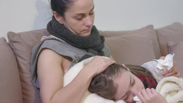 Worried mother touching forehead of ill daughter with fever