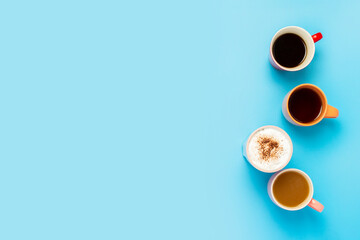 Cups with hot drinks, coffee, cappuccino, coffee with milk on a blue background. Concept coffee shop, meeting friends, breakfast with friends, friendly team. Banner. Flat lay, top view