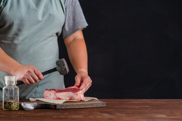 In front of the cook lies a meat tenderloin and the cook beats the entrecote with a special hammer
