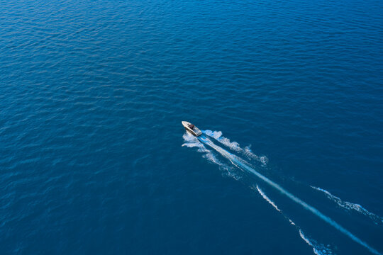 Large speed boat moving at high speed side view. Top view of a white boat sailing to the blue sea. Travel - image. Aerial view luxury motor boat.