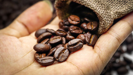 Fresh coffee beans roasted in the hands of men.