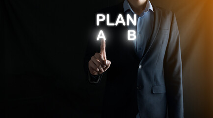 Businessman in a suit chooses options for plan development, Plan A, Plan B. on virtual screen. Business strategy, choosing a plan or decision concept.