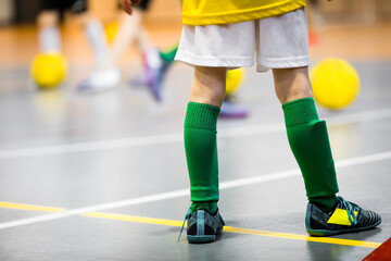 Soccer futsal training for children. Indoor football dribbling training. Kids with a soccer balls in a sports hall. Young player in soccer cleats, green socks and sporty uniform