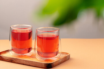 Two glass cups of black tea on beige table
