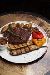 Ribeye steak with fried potatoes. Baked vegetables with beef steak on white plate