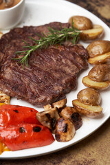 Ribeye steak with fried potatoes. Baked vegetables with beef steak on white plate