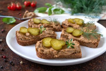 Canapes with chicken liver pate and pickled cucumbers on rye bread. Tasty and healthy appetizer.