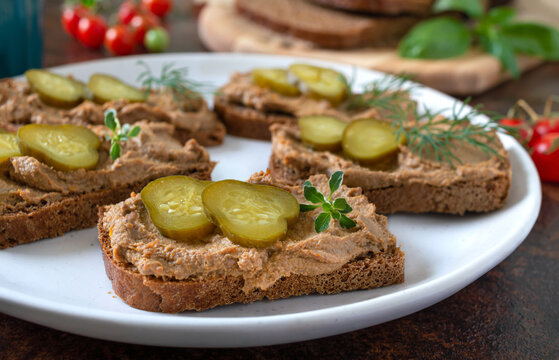 Canapes with chicken liver pate and pickled cucumbers on rye bread. Tasty and healthy appetizer.