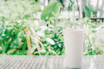 cool drink in white paper glass and paper straw on table with blurred green background , less plastic concept