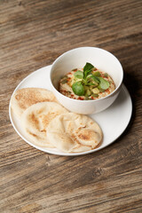 Hummus with avocado and herbs in white bowl