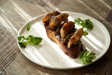 Toast with baked chicken liver on white plate on table