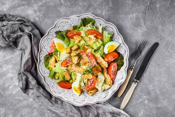  Caesar salad with chicken on a beautiful plate and gray concrete background top view