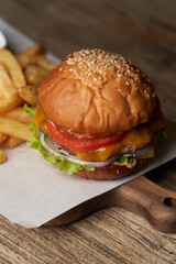 Fresh burger and french fries on wooden cutting board