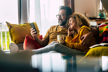 Adult caucasian couple at home enjoy phone call conference with friends - people and technology...