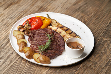 Ribeye steak with fried potatoes. Baked vegetables with beef steak on white plate