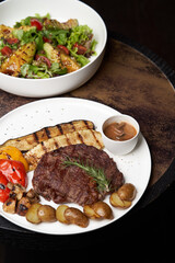 Ribeye steak with fried potatoes. Baked vegetables with beef steak on white plate