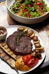 Ribeye steak with fried potatoes. Baked vegetables with beef steak on white plate