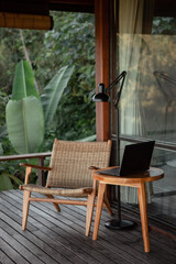 A wooden coffee table with a laptop and  on it, wooden wicker chair and mountain view