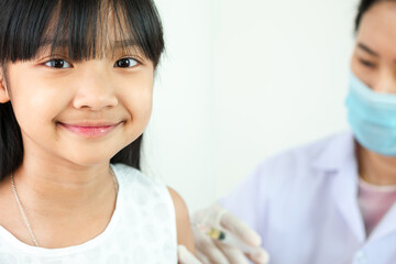 Asian child girl in a white shirt is vaccinating or taking medicine at the hospital with a smiling face on a white background