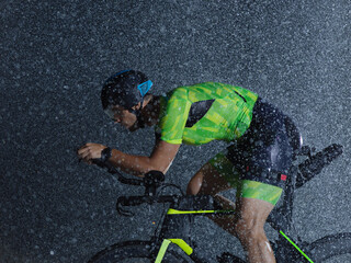 triathlon athlete riding bike on rainy night