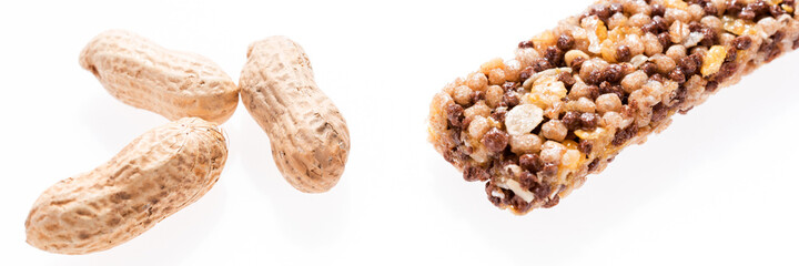 Healthy granola bar (muesli or cereal bar) and peanuts isolated on white. Panoramic image