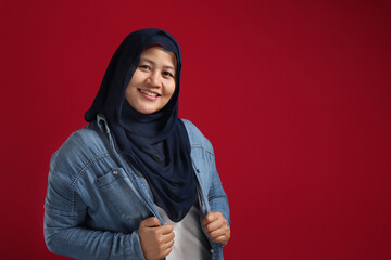 Portrait of beautiful Asian muslim woman wearing blue hijab smiling at camera over red