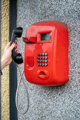 Woman using a public red telephone reaching out with her hand to take the handset off the cradle