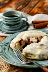 Glazed cinnabon bun in green plate on wooden table