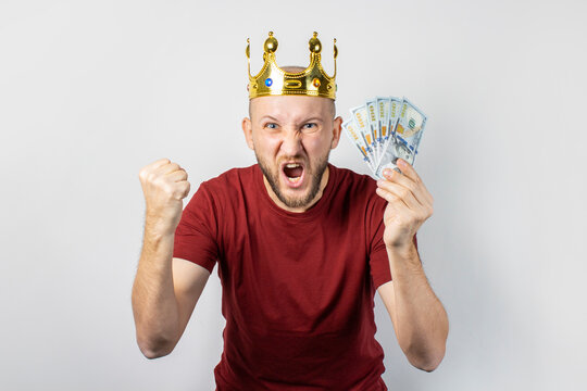 Young man in a golden crown holds money in his hands celebrates victory on a light background. Concept  king, luck, gain, rich, dream, goal, aspiration, bet. Banner