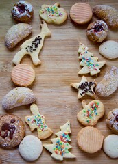 Selection of traditional homemade German Christmas cookies on a rustic wooden board, different figures, anise cookies, butter biscuits, vanilla crescents, nut biscuits, cookies with jam filling