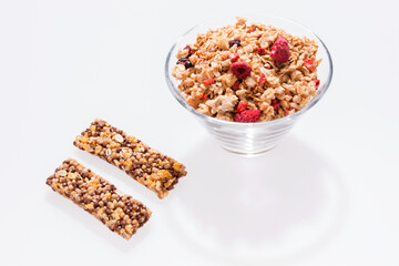 Two healthy granola bar and Muesli with red fruits in a glass bowl isolated on white
